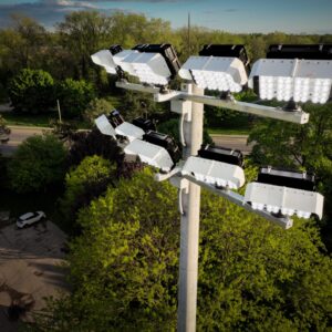 An assembled Spartan Sports Lighting project including KSL1 fixtures and cross arms atop a sports lighting pole. Project is overlooking sports field an is surrounded by trees.